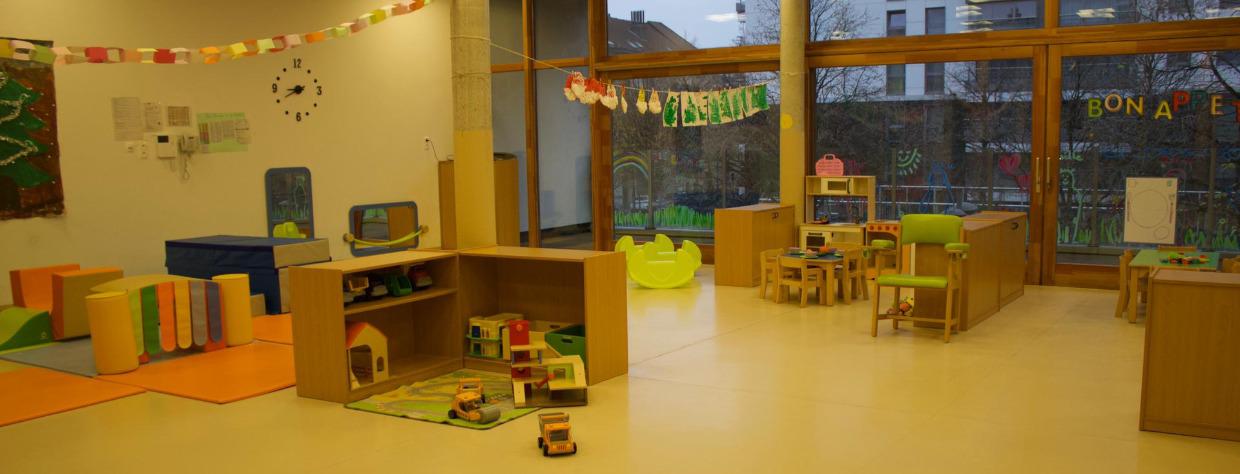 Grande salle avec coin de jeu avec des jouets en bois, table et chaises