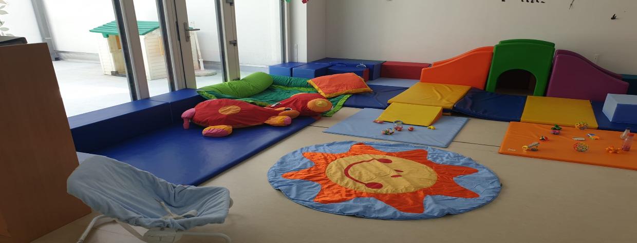 Salle d ejeu avec tapis, modules de jeu et vue sur la cour extérieure