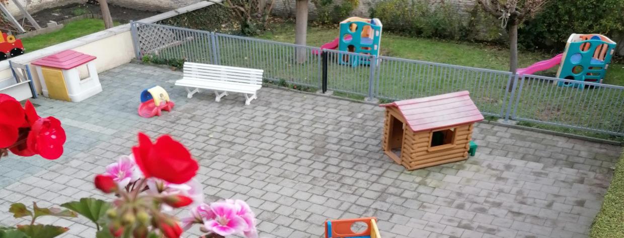 Terrasse avec maison en bois, banc et 2 tobogans dans le jardin