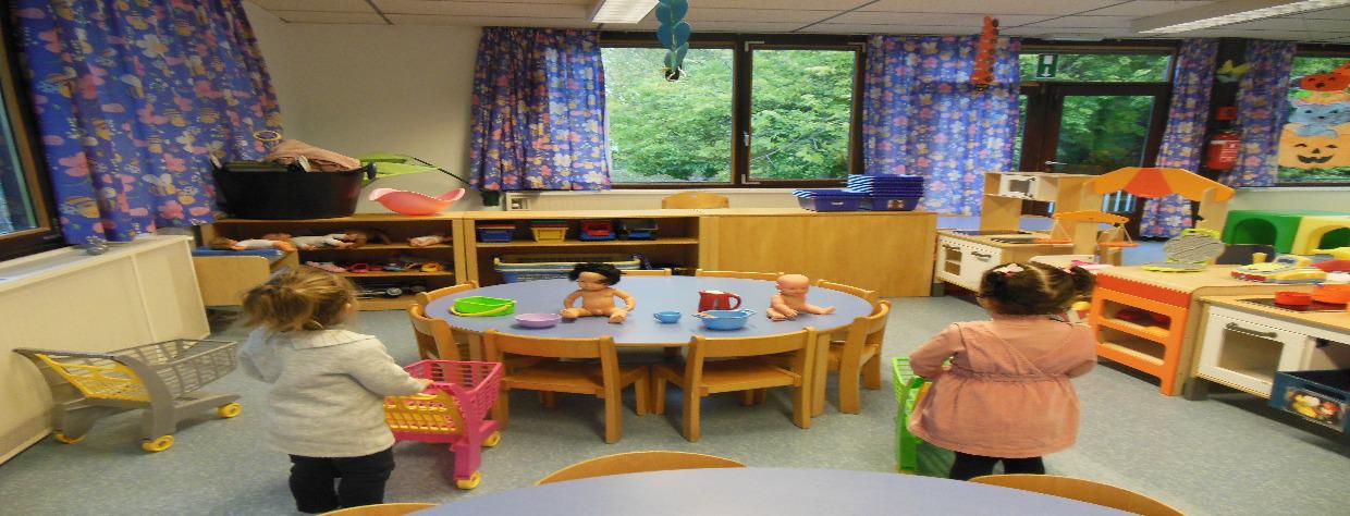 Deux petites filles jouent au magasin avec des petits caddies. Il y a une table sur laquelle sont posées deux poupées