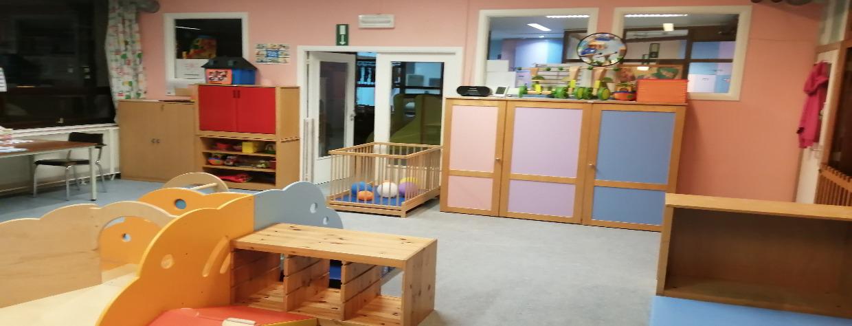 Salle avec un jeu constitué de moules en bois, parc en bois et armoires de rangement colorées