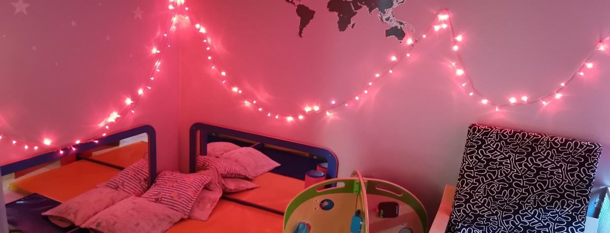 Coin repos avec des tapis et coussin ainsi qu'une guirlande lumineuse au mur, un siège et un jeu