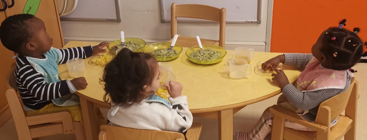 Trois enfants mangent assis à table