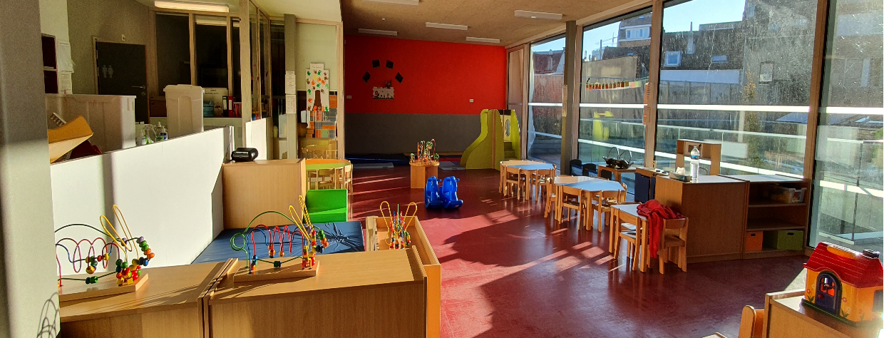 Grande salle avec tables et chaises et différents petits jouets